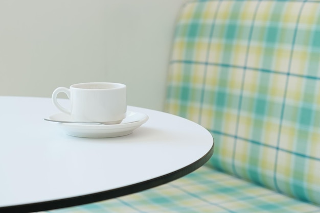 White coffee cup on a saucer on a round empty table