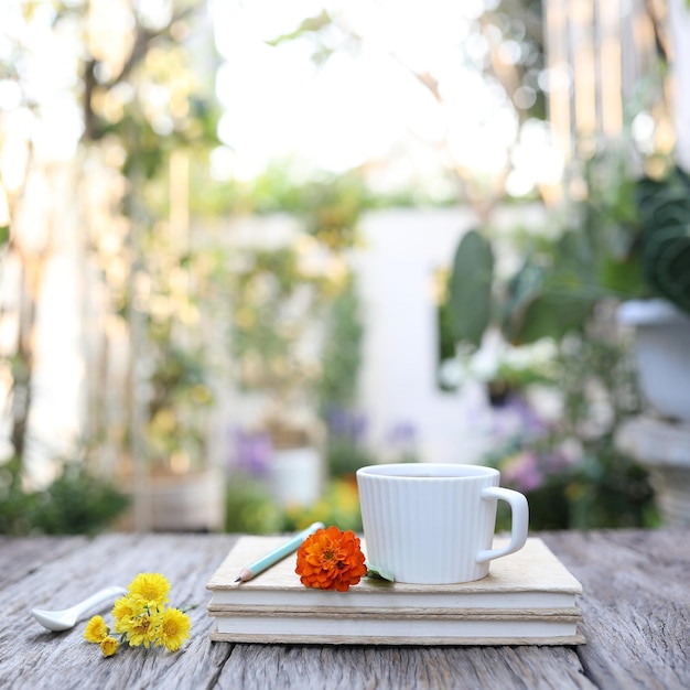 White coffee cup with flowers and notebooks on old wooden table