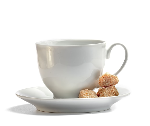 White coffee cup with saucer and brown cane unrefined sugar on a white