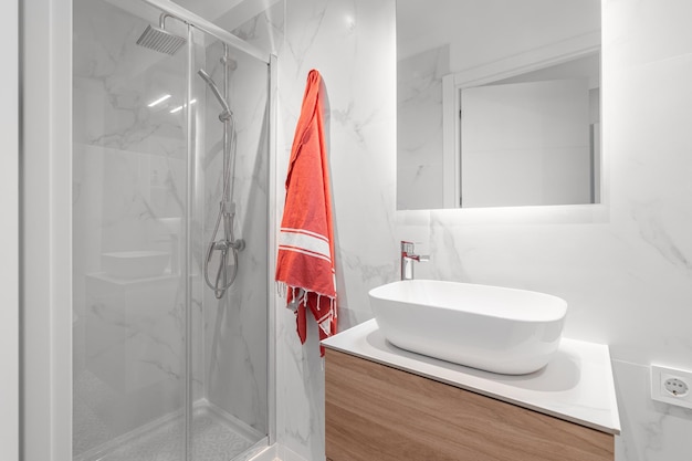 White compact bathroom with sink with mirror and glassenclosed shower with a stylish renovation