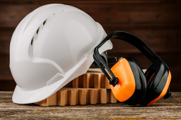 White construction helmet and orange headphones on a wooden background Protective headdress