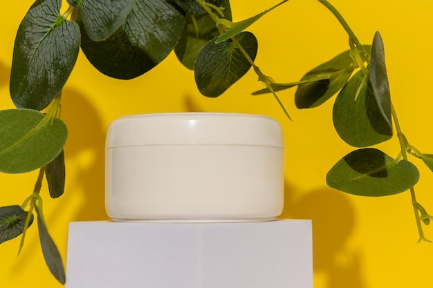 White containers on a white podium with green eucalyptus branches