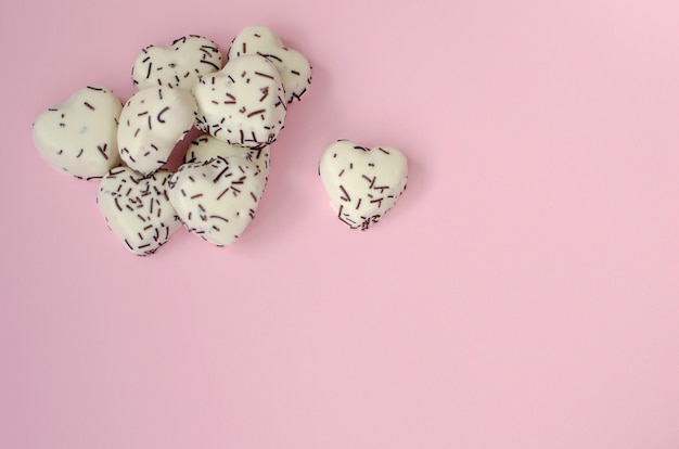 White cookies in heart shape on pastel pink background. copy space