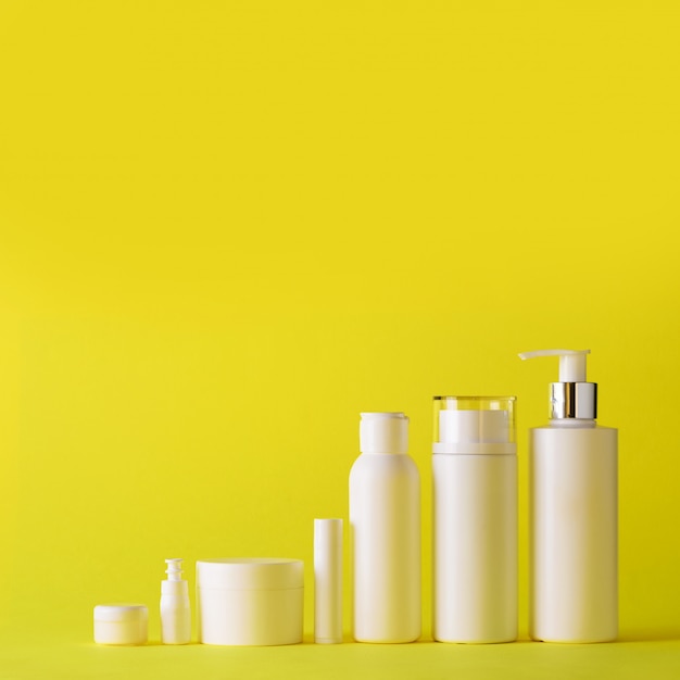 White cosmetic tubes on yellow background with copy space