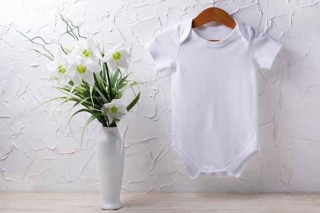 White cotton baby short sleeve onesie mockup with tender lily bouquet in the vase Design gender neutral bodysuit template newborn romper print presentation mock up