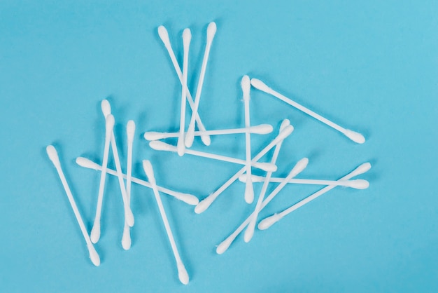 The white cotton buds with the white stem scattered on a blue background