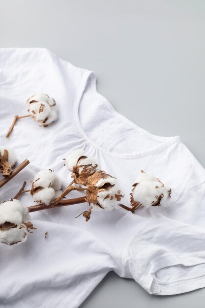 Photo white cotton tshirt and a branch of cotton on a gray background