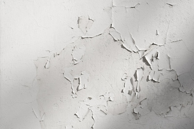 White cracked paint plaster on concrete wall outdoors Textured rough background