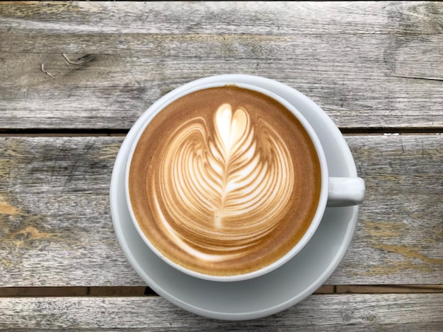 A White cup of cappuccino with latte art on wooden table background