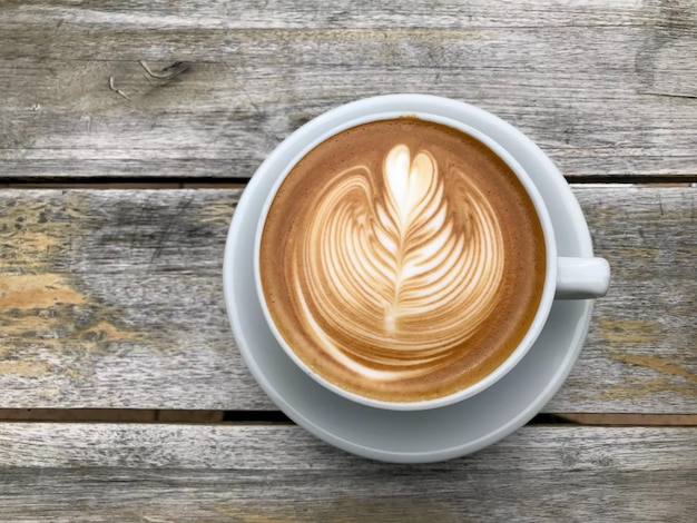 A White cup of cappuccino with latte art on wooden table background