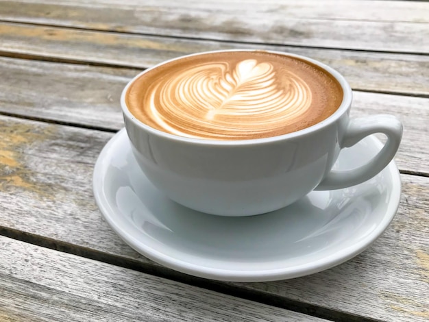 A White cup of cappuccino with latte art on wooden table background