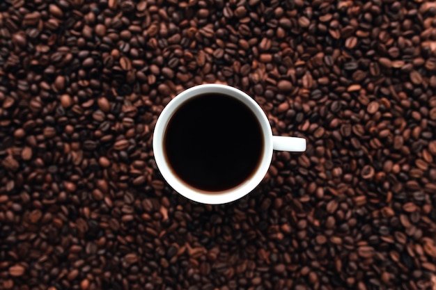 White cup of coffee on a bunch of roasted coffee beans background. High quality photo