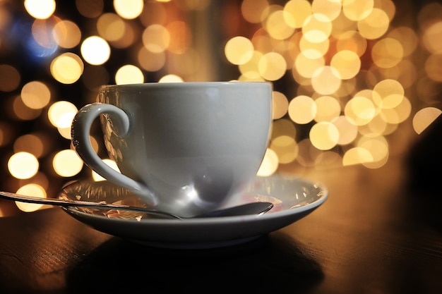 White cup of coffee on the table on blured background with circle bokeh