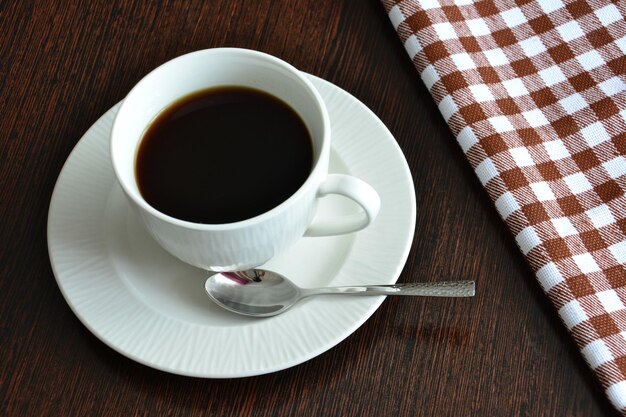 white cup of coffee with saucer and teaspoon isolated, close-up