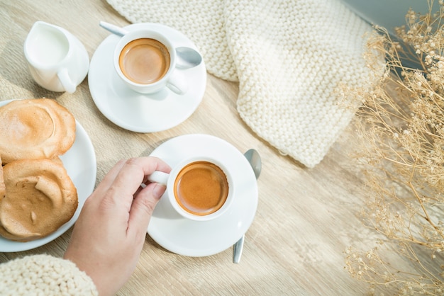 white cup of espresso coffee and meringue cookies on wooden table