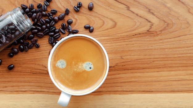 White cup of espresso coffee and Roasted coffee beans on a wooden background