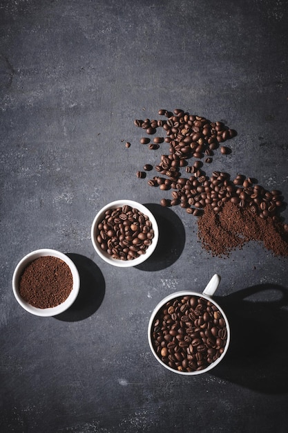 White cup of freshly brewed roasted coffee beans on gray background