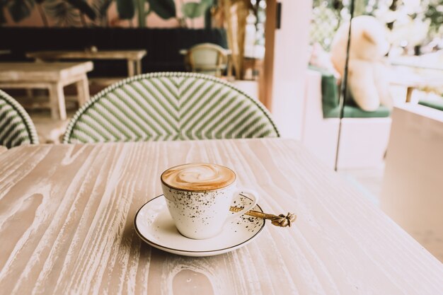 White cup of hot cappuccino on wooden light table background. breakfast time