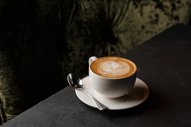 White cup of hot latte coffee with beautiful milk foam latte art texture isolated on dark background Overhead view copy space Advertising for cafe menu Coffee shop menu