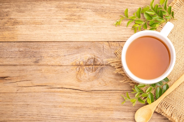 White cup of hot tea and dry tea leaf on wooden table