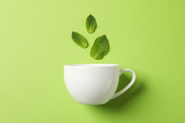 White cup and leaves on green, space for text