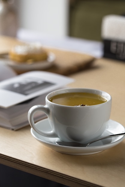 White cup of tea and book on a table in a cafe.