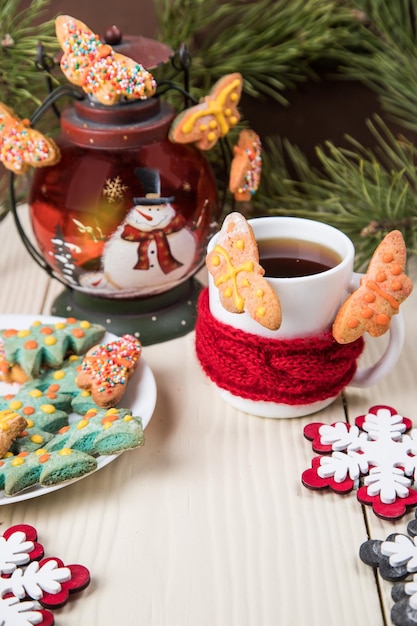 White Cup of tea in a red scarf with homemade butterfly cookies and a Christmas lantern