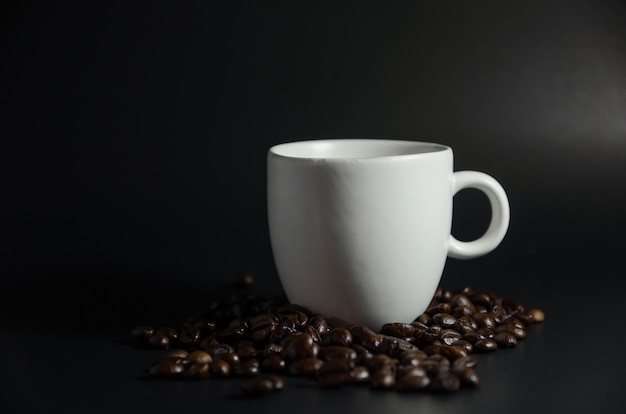 White cup with coffee beans in dark light