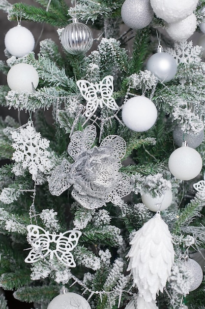 White decorative ball on the christmas tree on glitter bokeh background with blurred snow Happy New Year