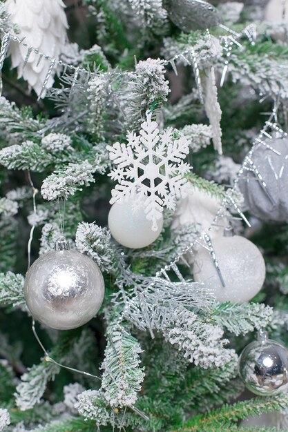 White decorative ball on the christmas tree on glitter bokeh background with blurred snow.