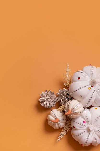 White decorative hand made pumpkins with shiny stones and pine cones on colored background Thanksgiving day concept