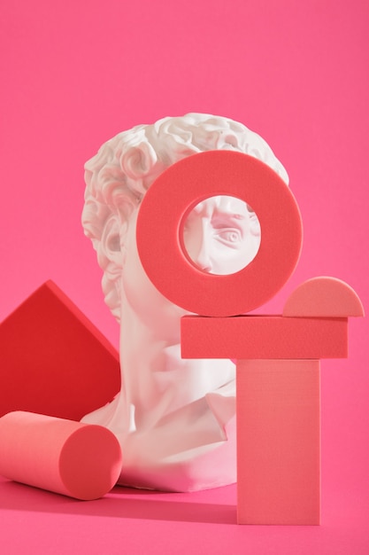 White decorative sculptural bust and several pink geometric coasters on a pink background