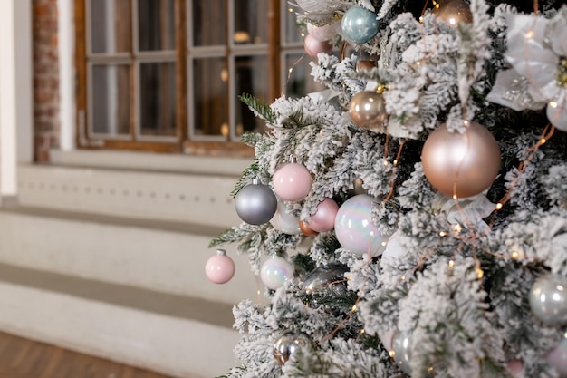 White delicate christmas tree and christmas decorations balls and ribbons garland and lights pink pe