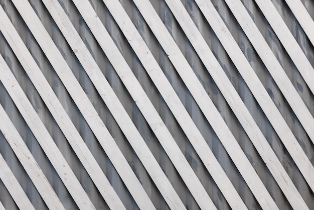 White diagonal wooden planks over gray corrugated metal sheet flat fullframe background and texture