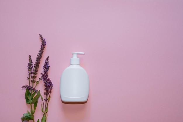 White dispenser with lavender flowers on a pink background. Copy space. Top view