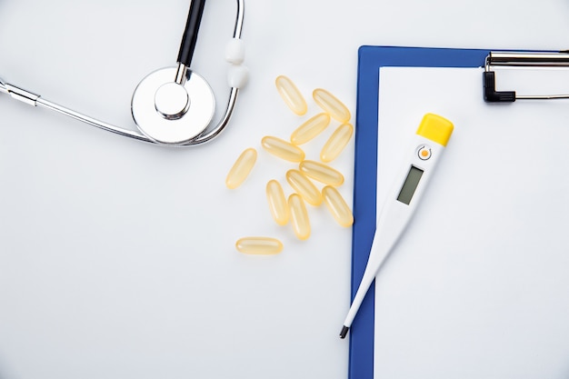 White doctor desk with pills stethoscope and thermometer