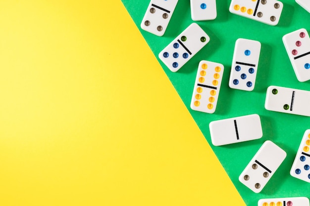 White dominoes with colorful dots on a yellowgreen background top view Board game Place for text