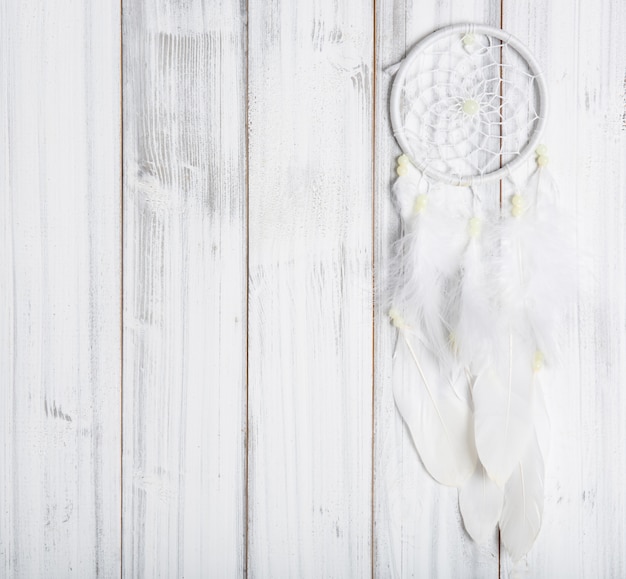 White dream catcher on wooden surface