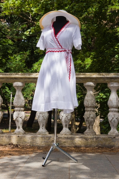 White dressing on mannequin White dress made of natural fabric with red elements Custom tailoring Women's summer cotton dress with belt