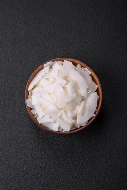 White dry coconut flakes in a wooden bowl prepared for making desserts