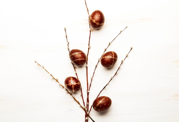 White Easter background with gold brown Easter eggs and willow branches Top view with copy space