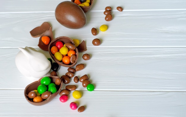 White Easter bunny with chocolate eggs and candies on white wooden 