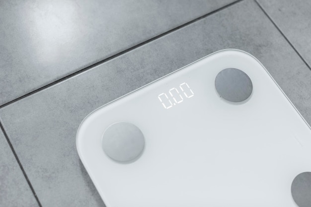 Photo white electric floor scales on grey tile floor displaying kilos closeup free space