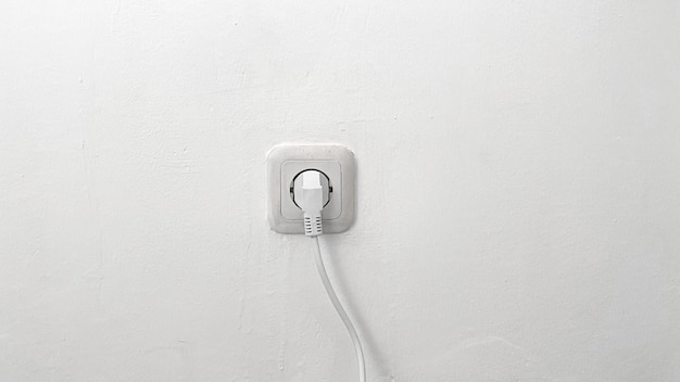 A white electrical outlet with a cord plugged into it.