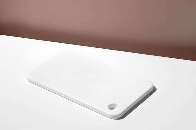 White empty marble board on white table Blank still life scene beige wall background with plate