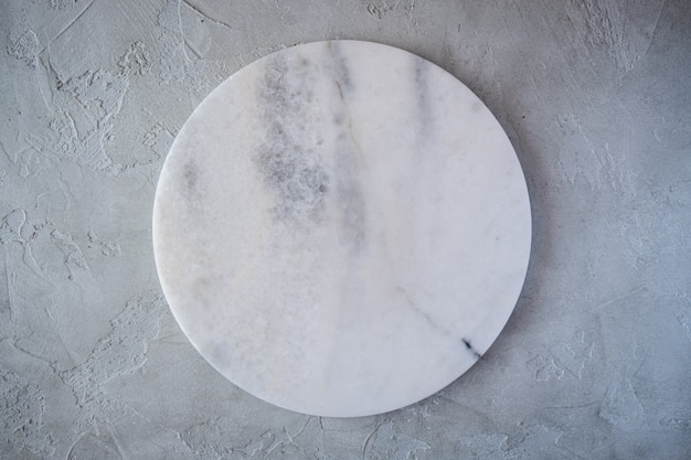 White empty marble texture round board on grey background. Top view. Copy space.