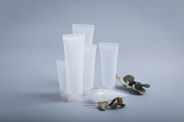 White empty plastic cosmetic tubes staying at gray