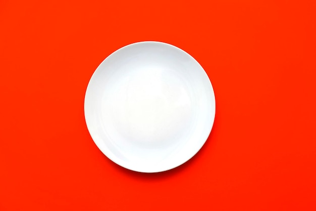 White empty plate with blank surface on bright red backdrop top view