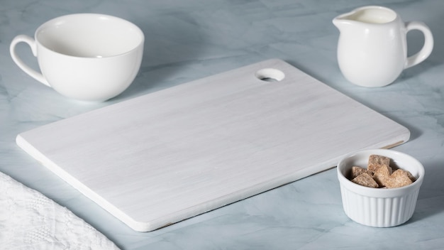 White empty wood board on green marble table Blank still life scene background with cup and plate