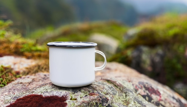 White enamel camping cup standing on rock Tasty beverage Delicious drink Morning in hiking camp